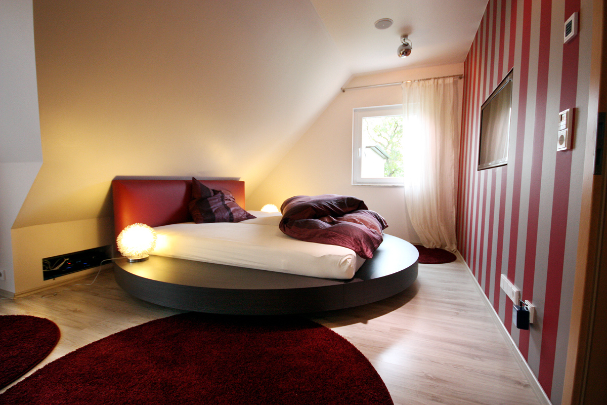 Ein modernes kreisrundes Bett unter der Dachschräge füllt den vorhandenen Platz optimal aus.